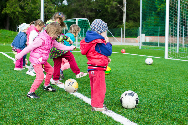 Children happily playing football. Their separated parents have used a child arrangement orders to agree who they live with, who they spend time with or have contact with and when.