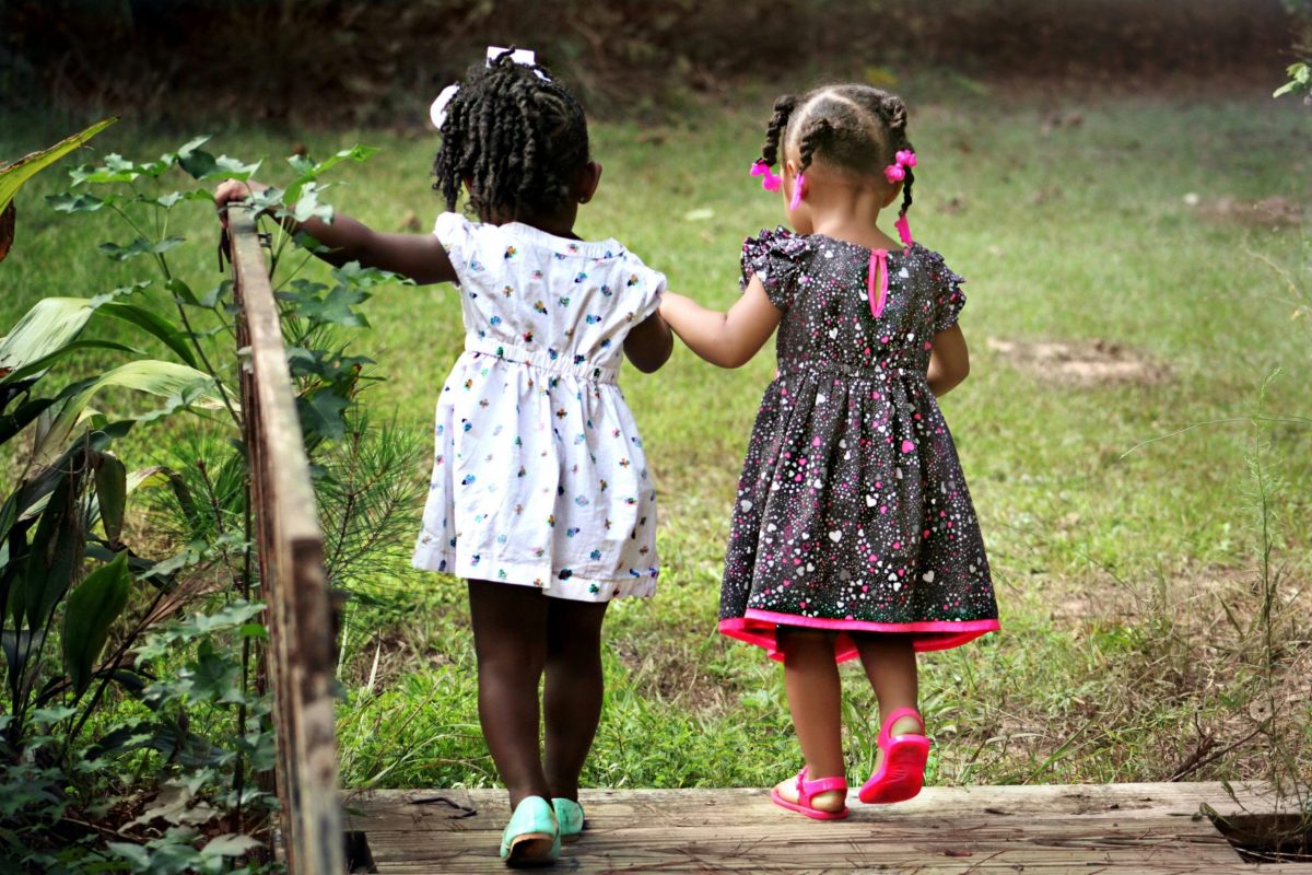 Two little girls cross a bridge holding hands whilst their parents are at a Dispute Resolution Appointment
