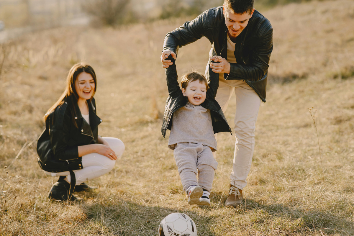 Parents playing football with a child. They are smiling because they understand how a separated parenting programme does and doesn't cover